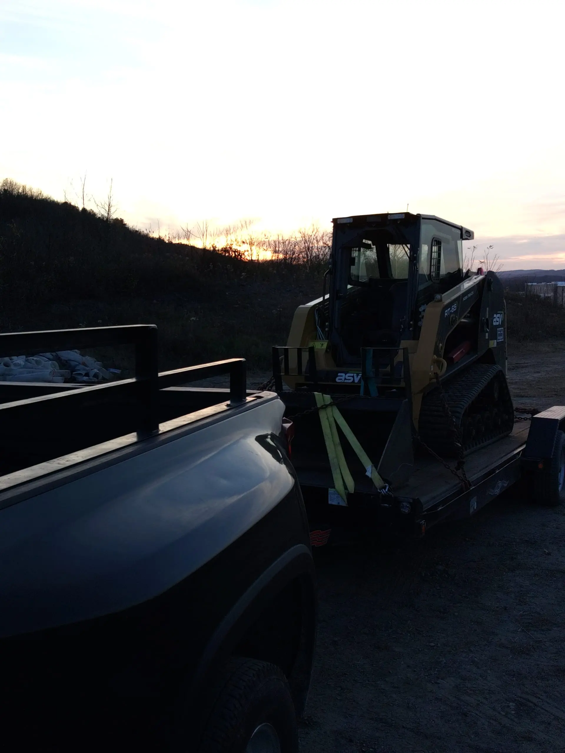 Tracked forestry mower loaded for transport at golden hour
